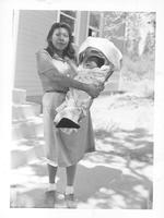Woman holding baby in basket.
