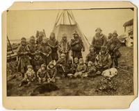 Group of men and children in front of tent.