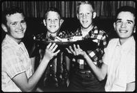 Group of boys holding a model of a ship.