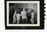 Boys listening to woman playing piano.